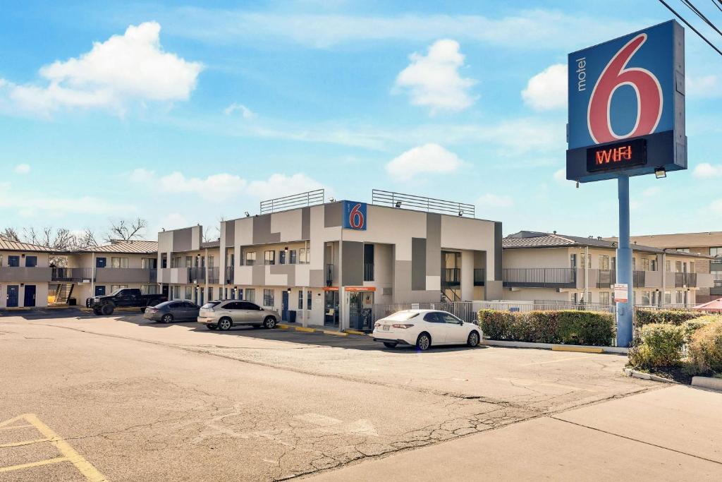 Motel 6-Austin, TX - South - Airport في أوستن: مبنى فيه سيارات متوقفة في موقف للسيارات