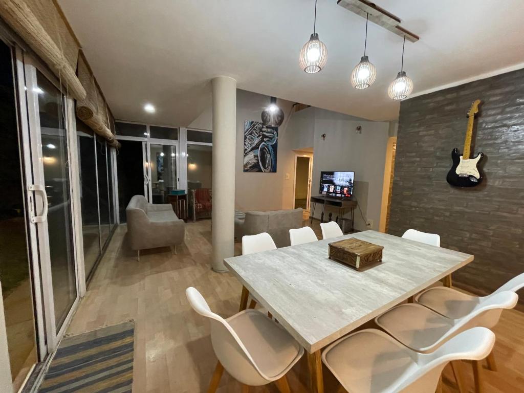 a dining room with a table and white chairs at Acordes de Chacras in Chacras de Coria