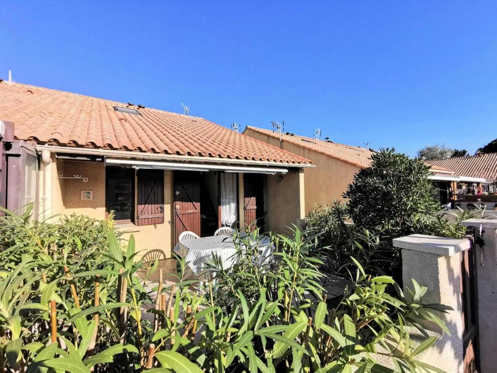une maison avec deux chaises blanches dans une cour dans l'établissement Résidence Village Merlin - VILLA T2 MEZZANINE 5 couchages PORT LEUCATE MAE-5824, à Leucate