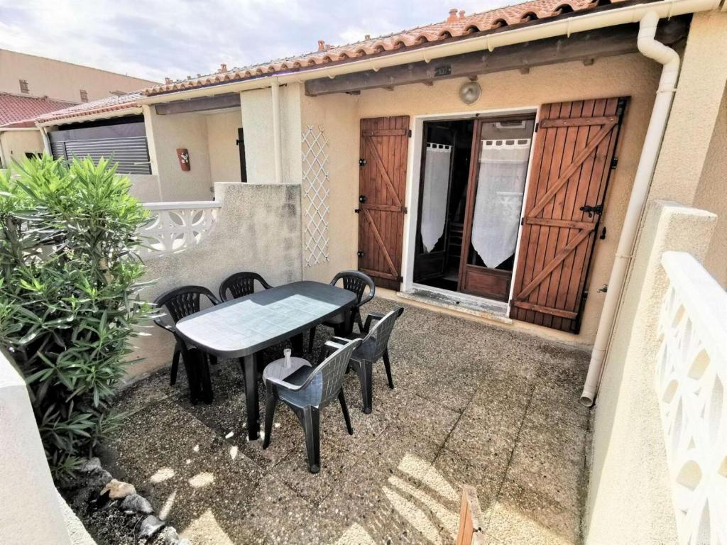 un patio avec une table et des chaises devant une maison dans l'établissement Résidence Grande Bleue - VILLA T1 CAB MEZZ 6 couchages PORT LEUCATE MAE-1604, à Leucate