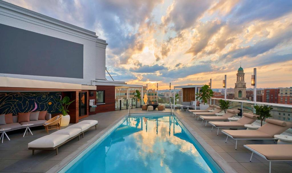 einen Pool auf der Dachterrasse des Hotels mit Liegestühlen und einem großen Bildschirm in der Unterkunft Hotel Zena Washington DC in Washington