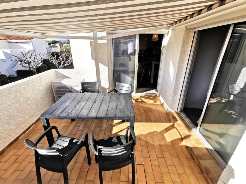 une table et des chaises en bois sur un balcon dans l'établissement Résidence Les Zodiaques - Appartement 3 Pièces climatisé 4 couchages PORT LEUCATE. Réf: 1ZOD_K5 MAE-6681, à Leucate