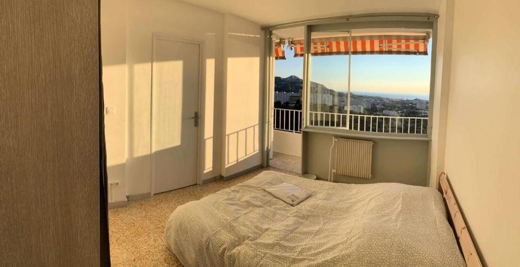une chambre avec un lit et un balcon avec vue dans l'établissement Résidence Rouviere - Grand appartement vue mer petit budget MAE-8124, à Marseille