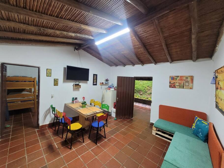 sala de estar con mesa, sillas y TV en Cabaña Caprichito en Piedecuesta