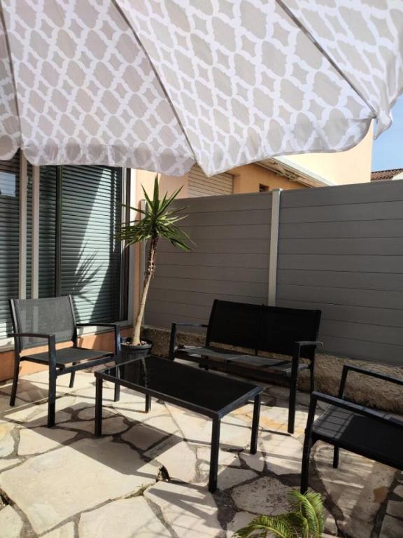une terrasse avec des chaises, des tables et un grand parasol dans l'établissement Résidence Marie Louise - Agréable appartement de 35m2 avec 4 couchages à Sanary-sur-Mer proche des plages MAE-9824, à Six-Fours-les-Plages