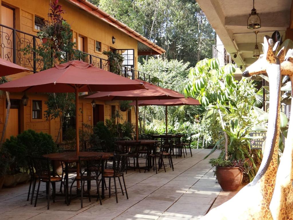 an outdoor patio with tables and chairs and umbrellas at Ikweta Country Inn Maua in Kaathene