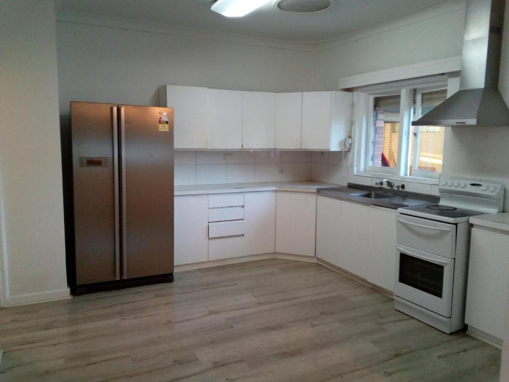 a kitchen with white cabinets and a stainless steel refrigerator at Homestay upon Kenwick Station in Perth