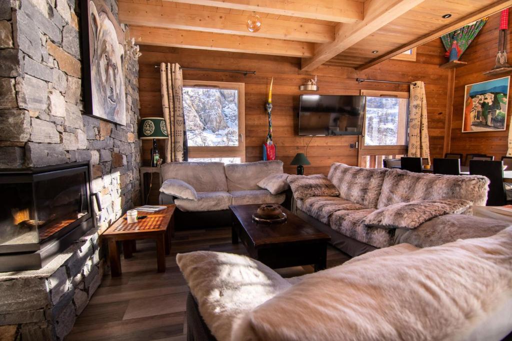 a living room with couches and a stone fireplace at Chalet KopÉrek - Chalets pour 12 Personnes 514 in Valloire