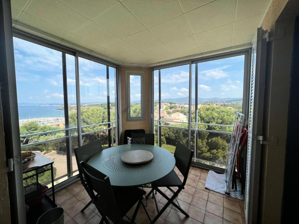 - une table à manger et des chaises dans une pièce avec fenêtres dans l'établissement Résidence Grand Large - Appartement T3 remis a neuf MAE-1034, à Six-Fours-les-Plages