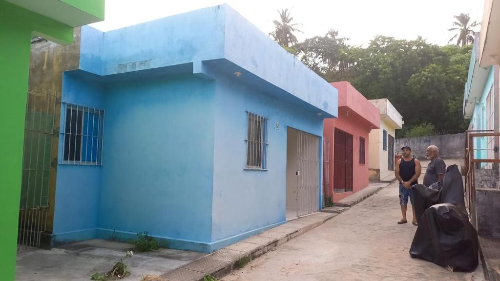 dos personas parados fuera de un edificio azul en Casa de praia Itamaracá em Jaguaribe en Jaguaribe