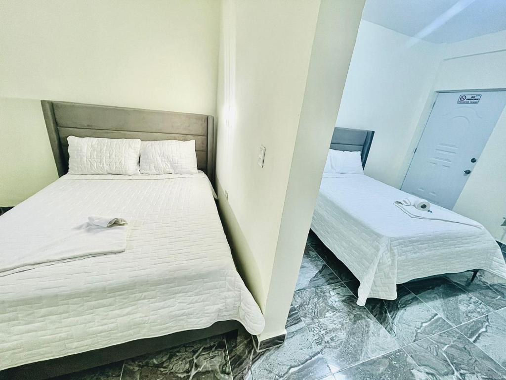 um quarto com 2 camas e lençóis brancos em Neo’s hotel em Santa Cruz de Barahona