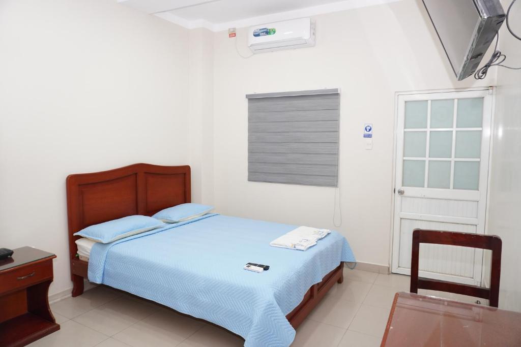 1 dormitorio con cama, mesa y ventana en Hotel SMIR en Huaquillas