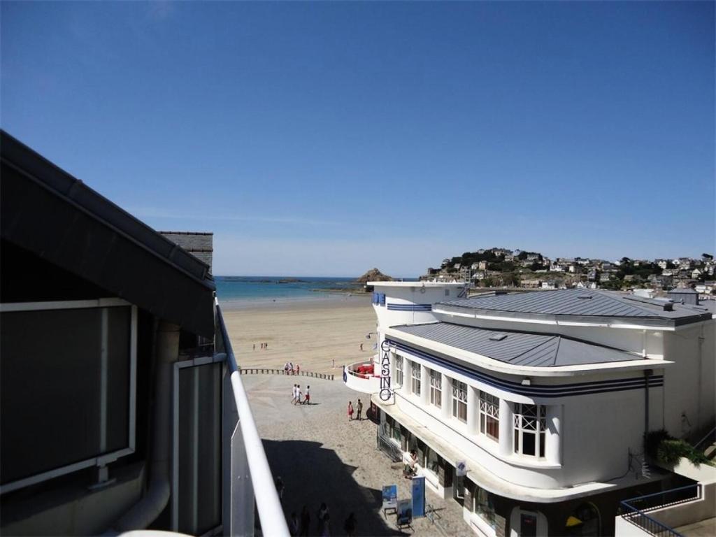 une vue d'une plage avec un bâtiment et l'océan dans l'établissement Résidence Les Bains - Charmant duplex à 50m de la promenade du Val André. MAE-6594, à Pléneuf-Val-André