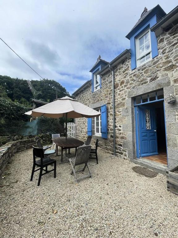 un patio avec une table, des chaises et un parasol dans l'établissement Résidence 740-pleneuf Val Andre - Belle maison en pierre offrant de beaux volumes dans la campagne de Pleneuf Val André MAE-8554, à Pléneuf-Val-André