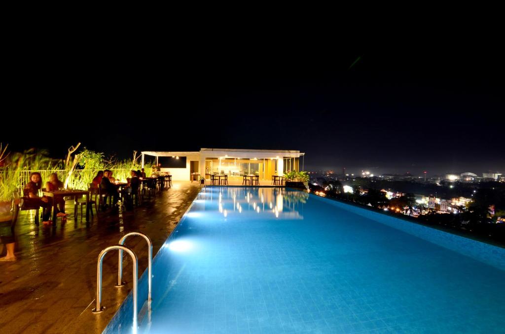 a swimming pool at night with a view of a city at Student Park Hotel in Yogyakarta