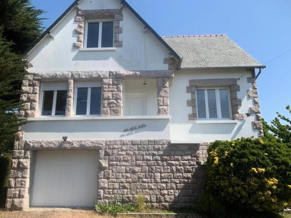 une maison blanche avec un garage en face dans l'établissement Résidence 620-pleneuf Val Andre - Belle maison néo-bretonne dans un quartier résidentiel sur les hauteurs du Val André MAE-7614, à Pléneuf-Val-André