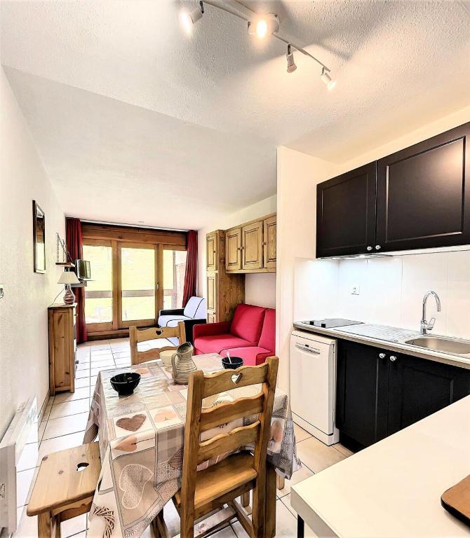 Il comprend une cuisine et un salon avec une table et un canapé rouge. dans l'établissement Résidence Cosmos - STUDIO 4 PERSONNES COSMOS MAE-9634, au Corbier