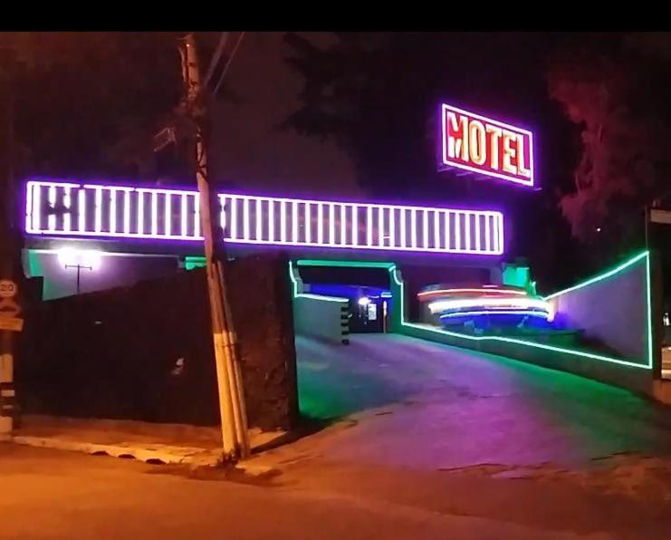 a motel with neon signs on a street at night at Motel Disco Verde Congonhas 1 in São Paulo