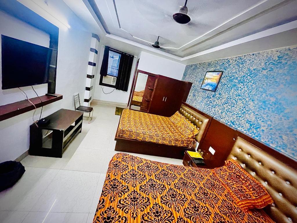 a hotel room with two beds and a television at Hotel AC family Rooms in Nagla Dhīmar