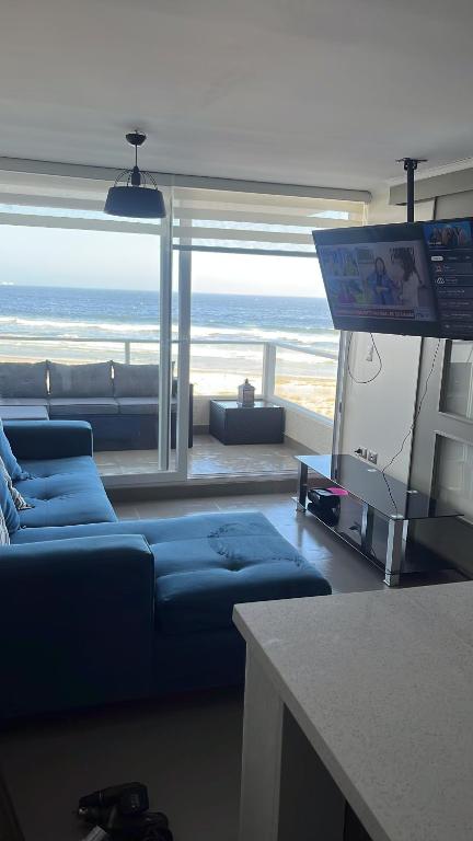 un salon avec un canapé bleu et une télévision dans l'établissement Resort Laguna del mar, à La Serena