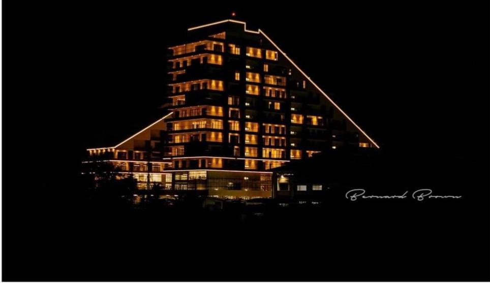 ein hohes Gebäude mit nachts eingeschaltetem Licht in der Unterkunft M.R APARTMENTS in Accra