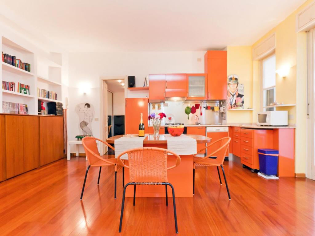 eine Küche mit orangefarbenen Schränken sowie einem Tisch und Stühlen in der Unterkunft Italianway-Vallazze in Mailand