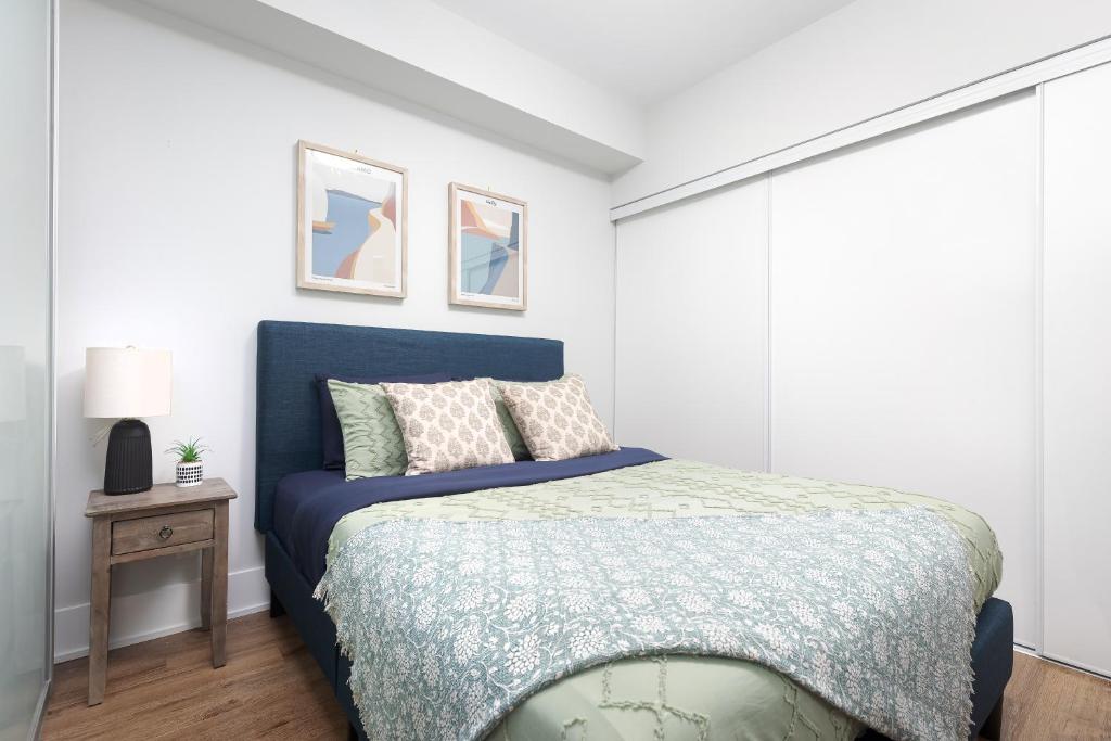 a bedroom with a bed with a blue bedspread at 3 Beds w/ CN Tower View Right Beside Rogers Centre! in Toronto