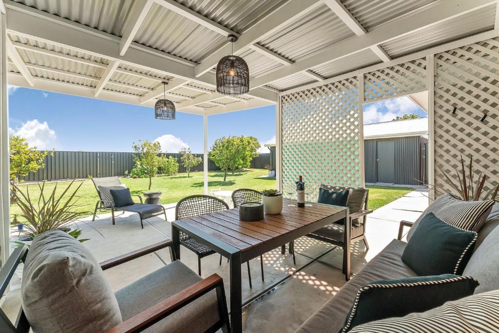 an outdoor patio with a wooden table and chairs at Belle Escapes - Bountiful Family Oasis in West Beach in Henley Beach South
