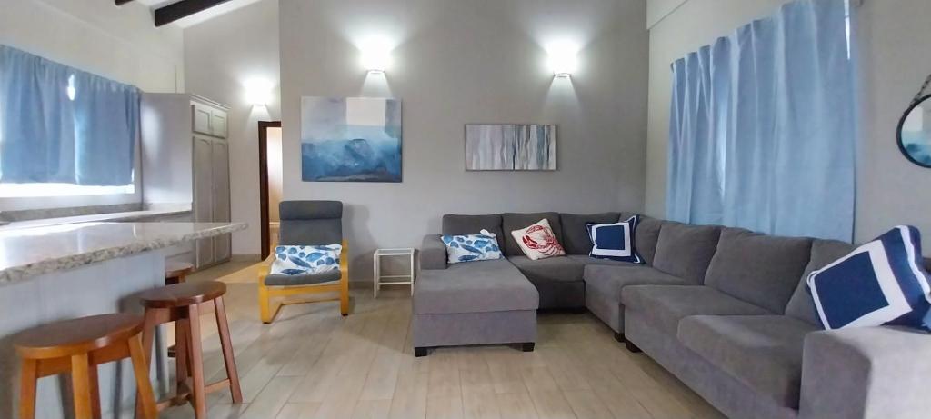 sala de estar con sofá gris y sillas en Casa Palma Placencia en Placencia Village
