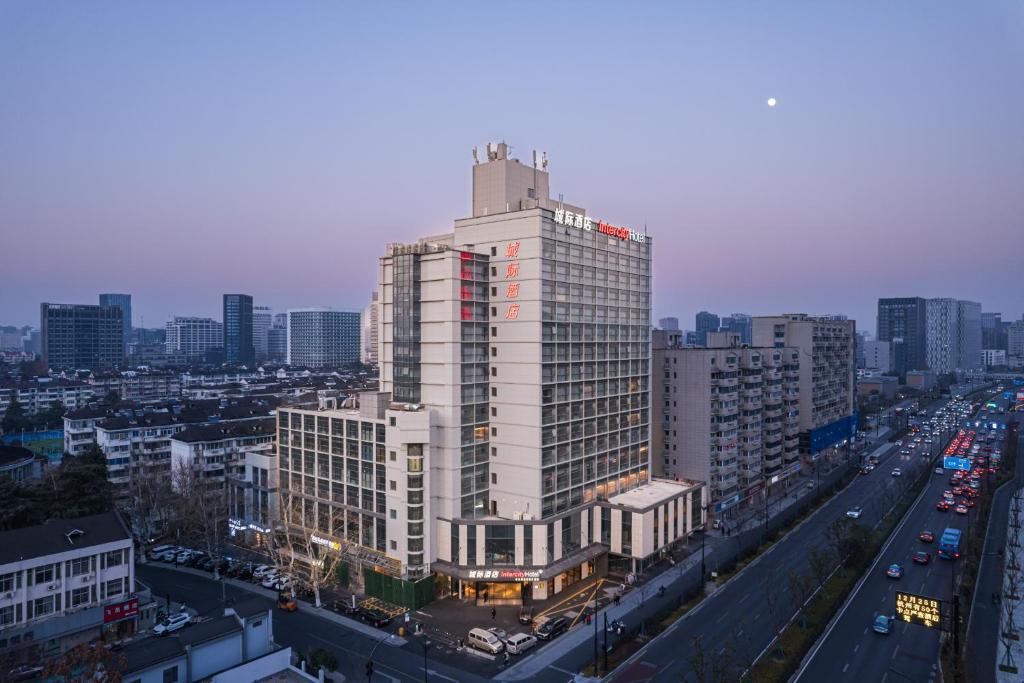 a tall white building in the middle of a city at Intercity Hangzhou West Lake Huanglong Hotel in Hangzhou