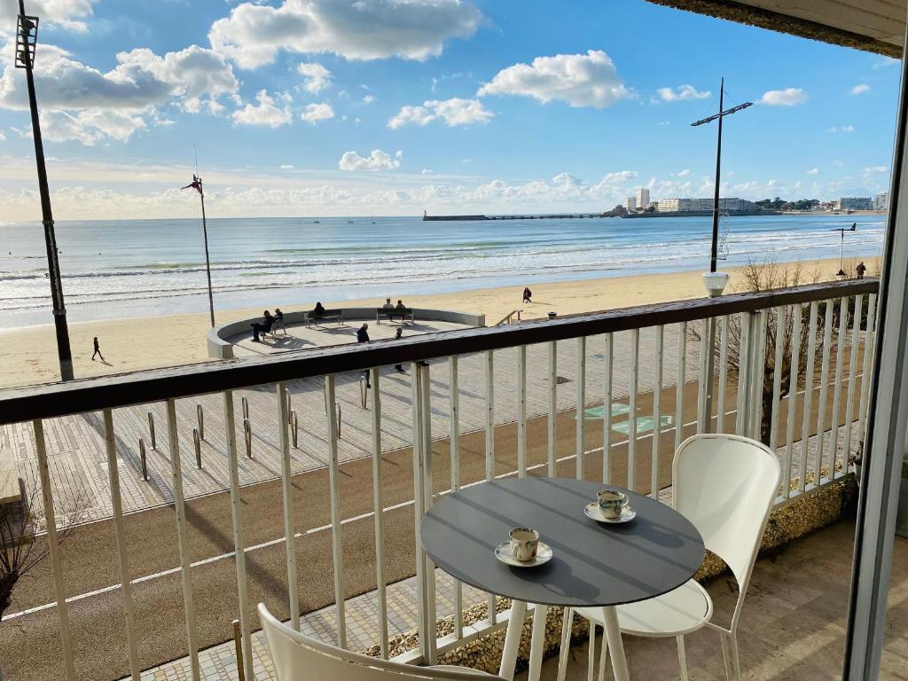 - un balcon avec une table et des chaises et la plage dans l'établissement Appartement avec accès direct à la plage, balcon et garage privé - FR-1-92-690, à Les Sables-dʼOlonne