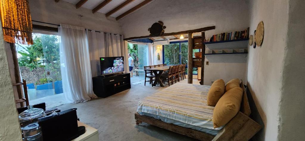 Schlafzimmer mit einem Bett, einem TV und einem Tisch in der Unterkunft Bangalô com Vista Parcial para o Mar in São Sebastião