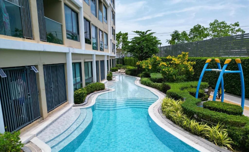 a swimming pool in front of a building at Resort Style Condo Suksawat 64 Bangkok ND in Ban Tha Hin