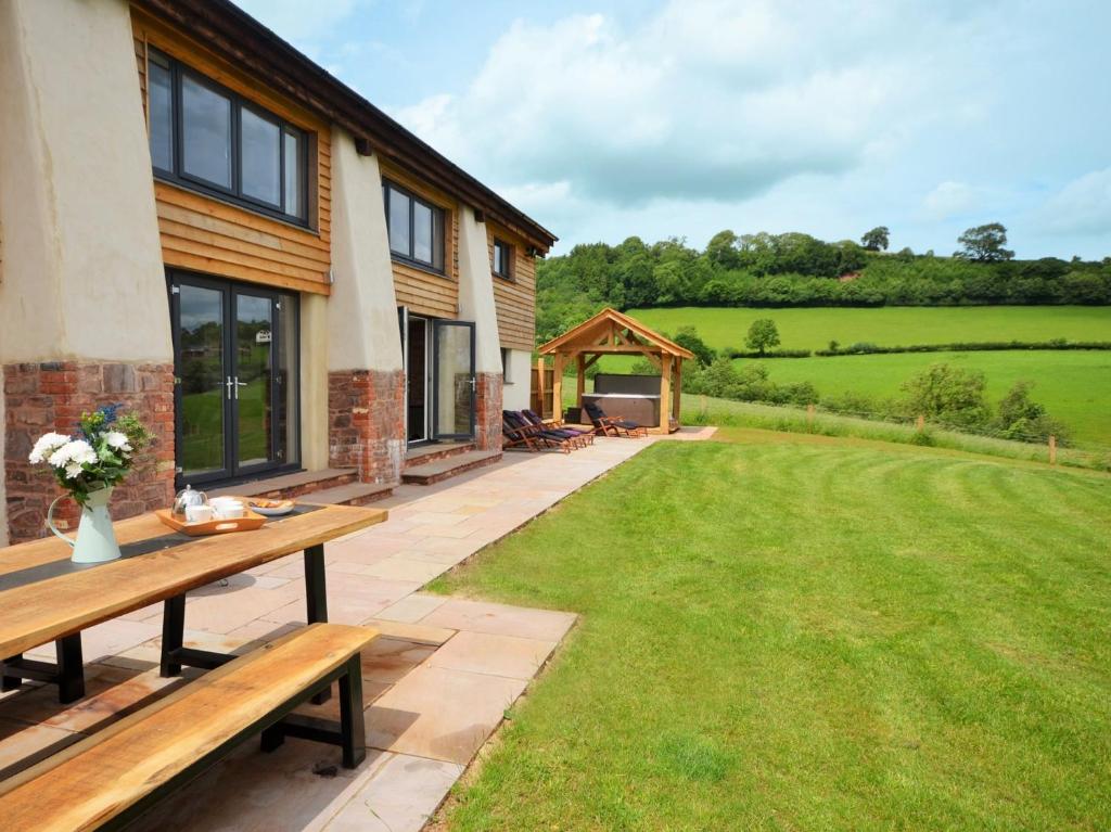 a garden with a wooden table and a lawn at 5 Bed in Tiverton 48151 in Cadeleigh