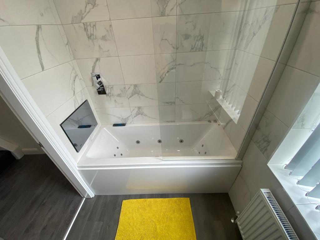 La salle de bains est pourvue d'une baignoire blanche et d'un tapis jaune. dans l'établissement Entire Southgate House, à Elland