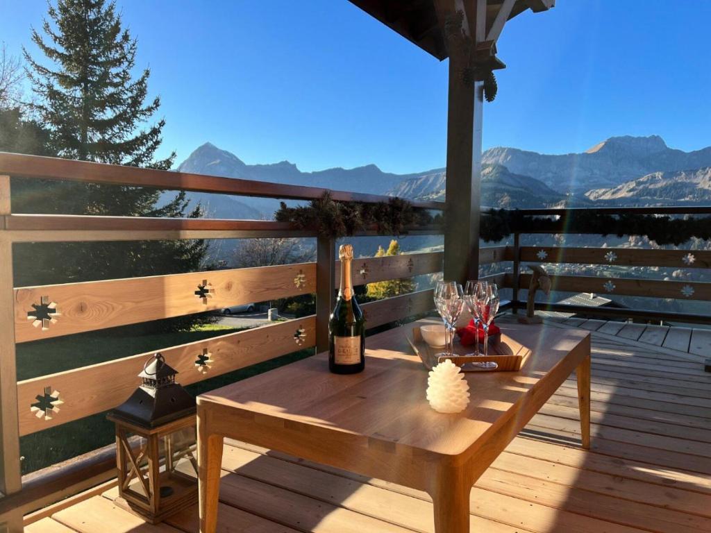 una terraza de madera con una mesa y una botella de vino en Résidence Le Cristal - Chalets pour 8 Personnes 154 en Crest-Voland