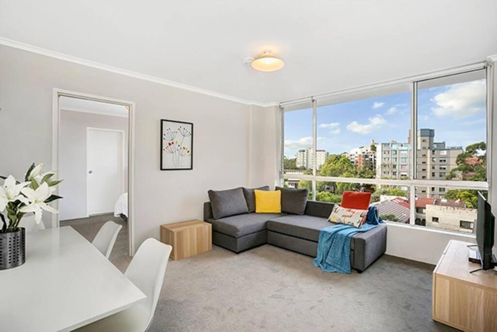 a living room with a couch and a large window at RAND3 - Cosy Apartment - Great Location, Easy CBD Access in Sydney