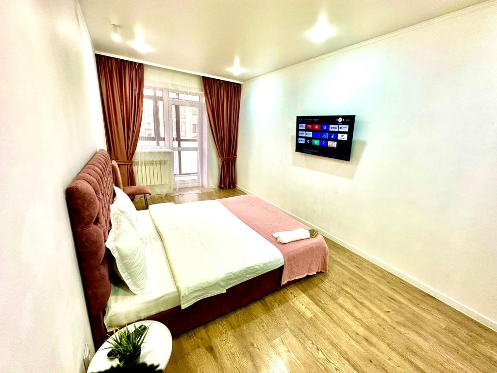 een slaapkamer met een bed en een flatscreen-tv bij ЖК МАДИНА ЕВРА ДВУШКА in Köksetaw