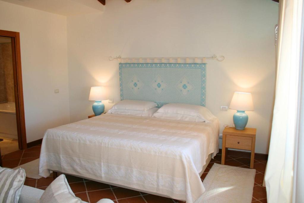 a bedroom with a bed with a blue headboard and two lamps at Hotel Marana in Golfo Aranci