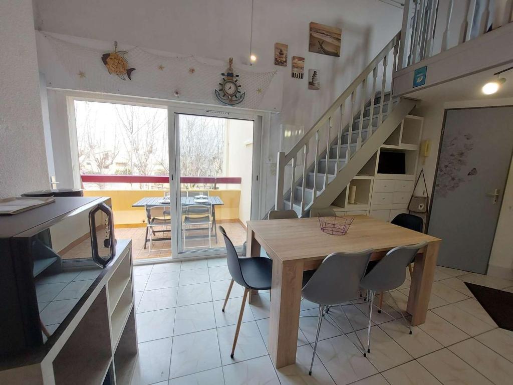 a kitchen and dining room with a wooden table and chairs at Appartement Marseillan-Plage, 2 pièces, 6 personnes - FR-1-326-798 in Marseillan