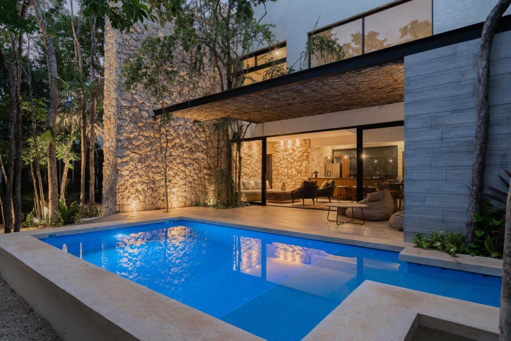 a swimming pool in front of a house at Twelve O'Clock - Luxury Villas in Tulum