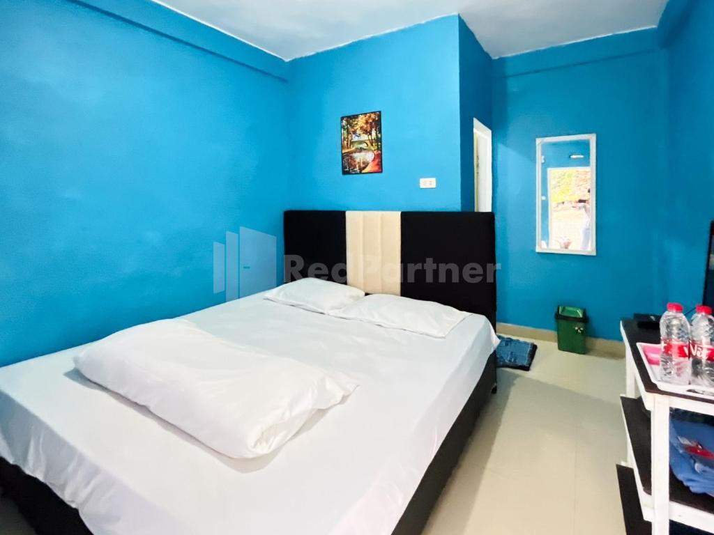 a bedroom with blue walls and a white bed at Penginapan Gindo Sidebuk Debuk Berastagi RedPartner in Berastagi