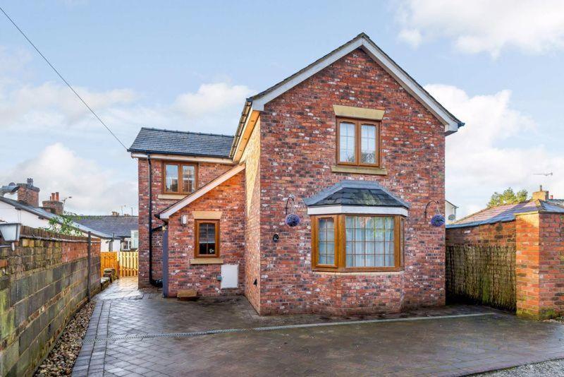 a brick house with a fence in front of it at Tarporley Holiday Cottage in Tarporley