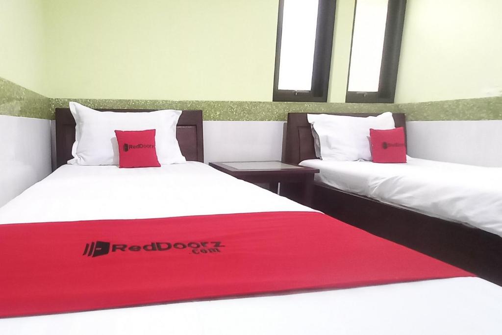 two beds with red pillows in a room at RedDoorz Syariah near Bypass Krian in Gabung