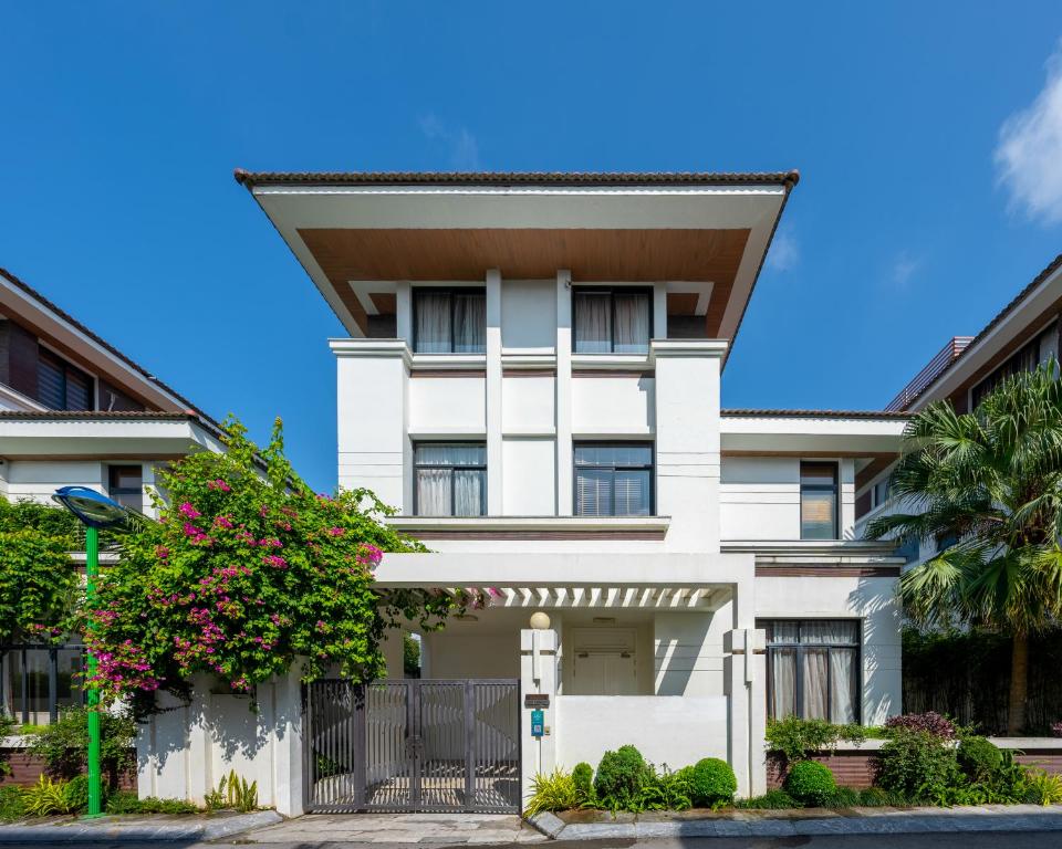 een wit huis met een hek en bloemen bij Mint Village Hạ Long in Ha Long