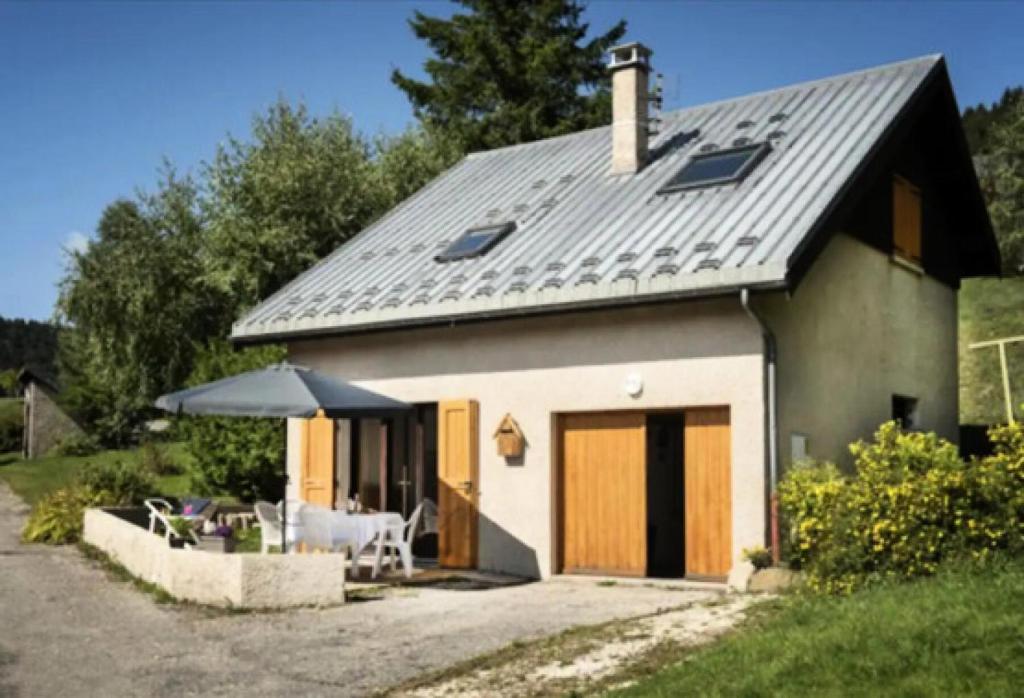 a small house with a pitched roof with a patio at Résidence Le Petit Nid - Maisons & Villas pour 7 Personnes 324 in Corrençon-en-Vercors