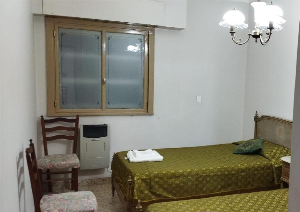 a bedroom with a bed and a window and a chair at Plaza Libertad in Santiago del Estero