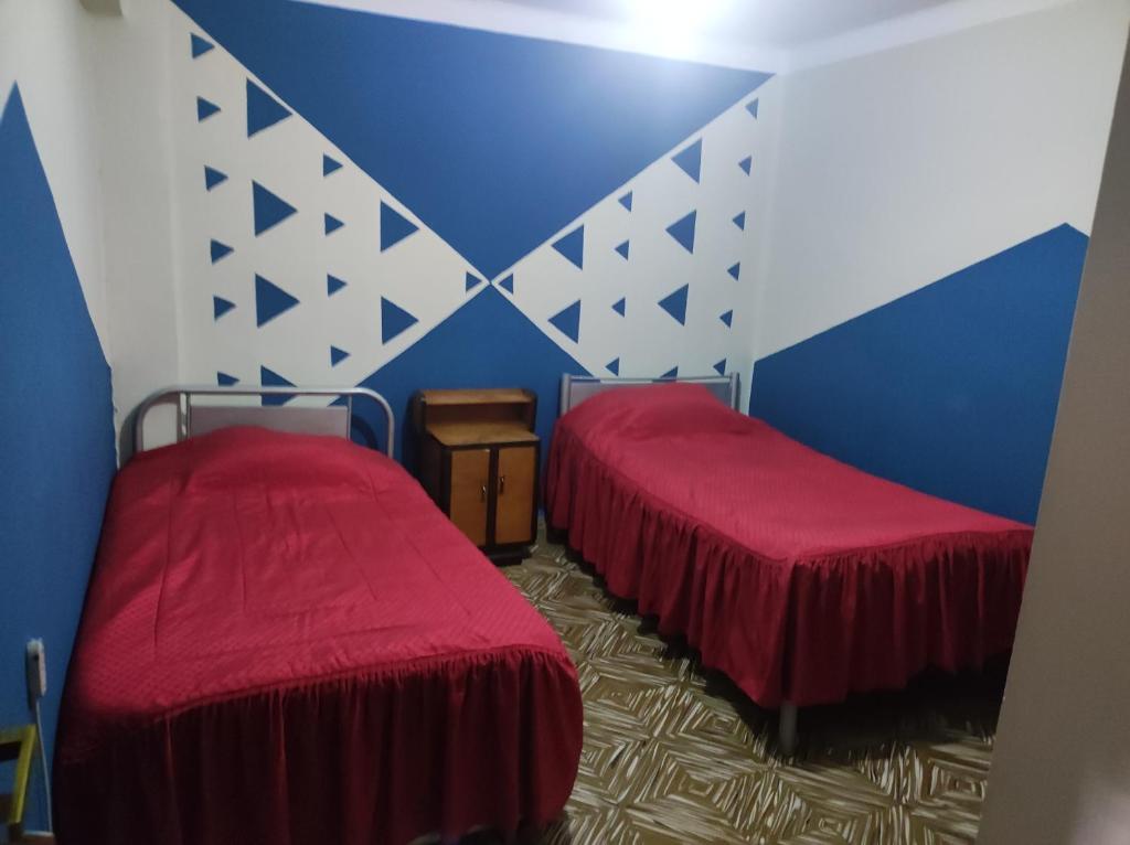 2 letti con coperte rosse in una camera di HOTEL AMERICA a Tarija