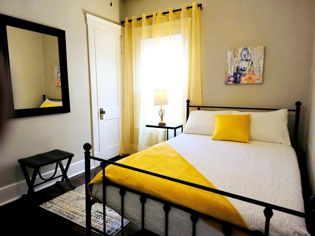 a bedroom with a bed with a yellow blanket and a mirror at Charming! near CLE Clinic/UH/CWRU/Dwntwn w/porch in Cleveland