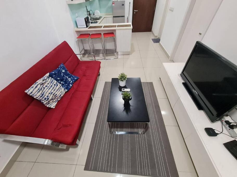 a living room with a red couch and a coffee table at AZ Apartment @ Cyberjaya Netflix Wi-Fi in Cyberjaya